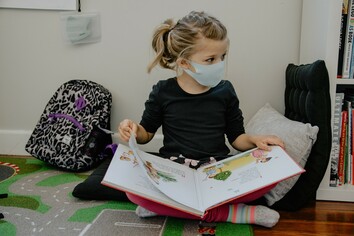 student wearing a mask reading a book